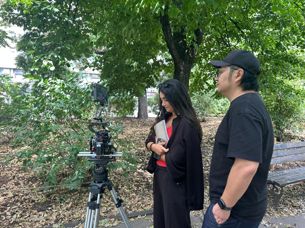 Tracy Greige reviewing a cinema camera monitor in a Prague park