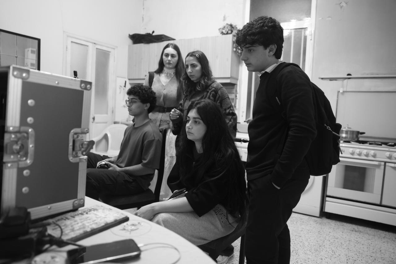 Black-and-white image of the Soi team reviewing a monitor