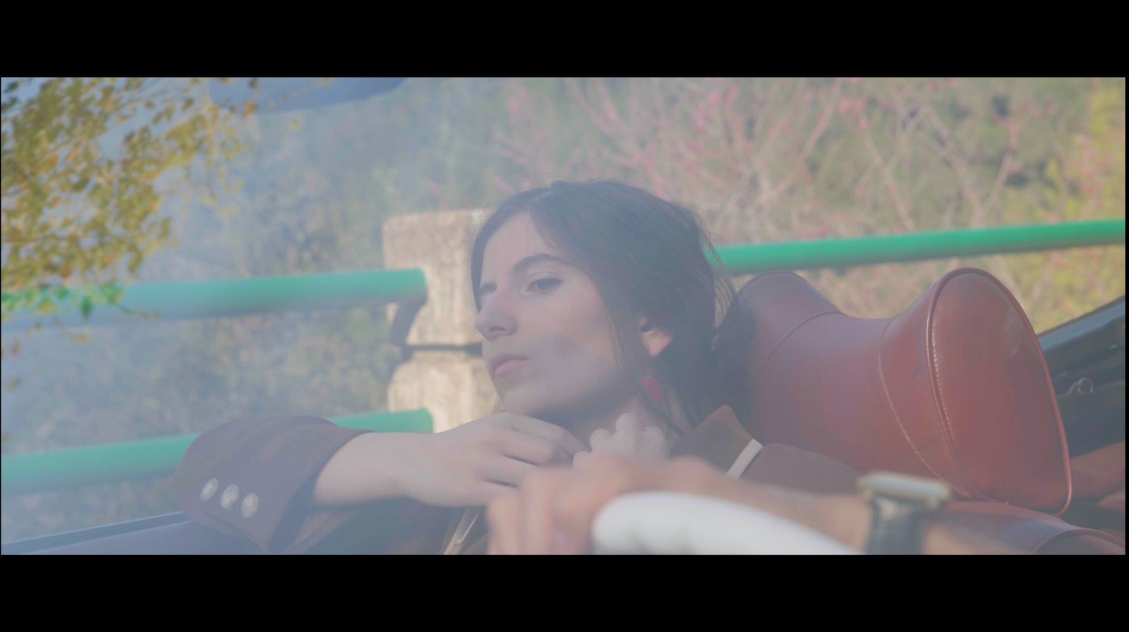 Film still of a woman seated in a vintage convertible