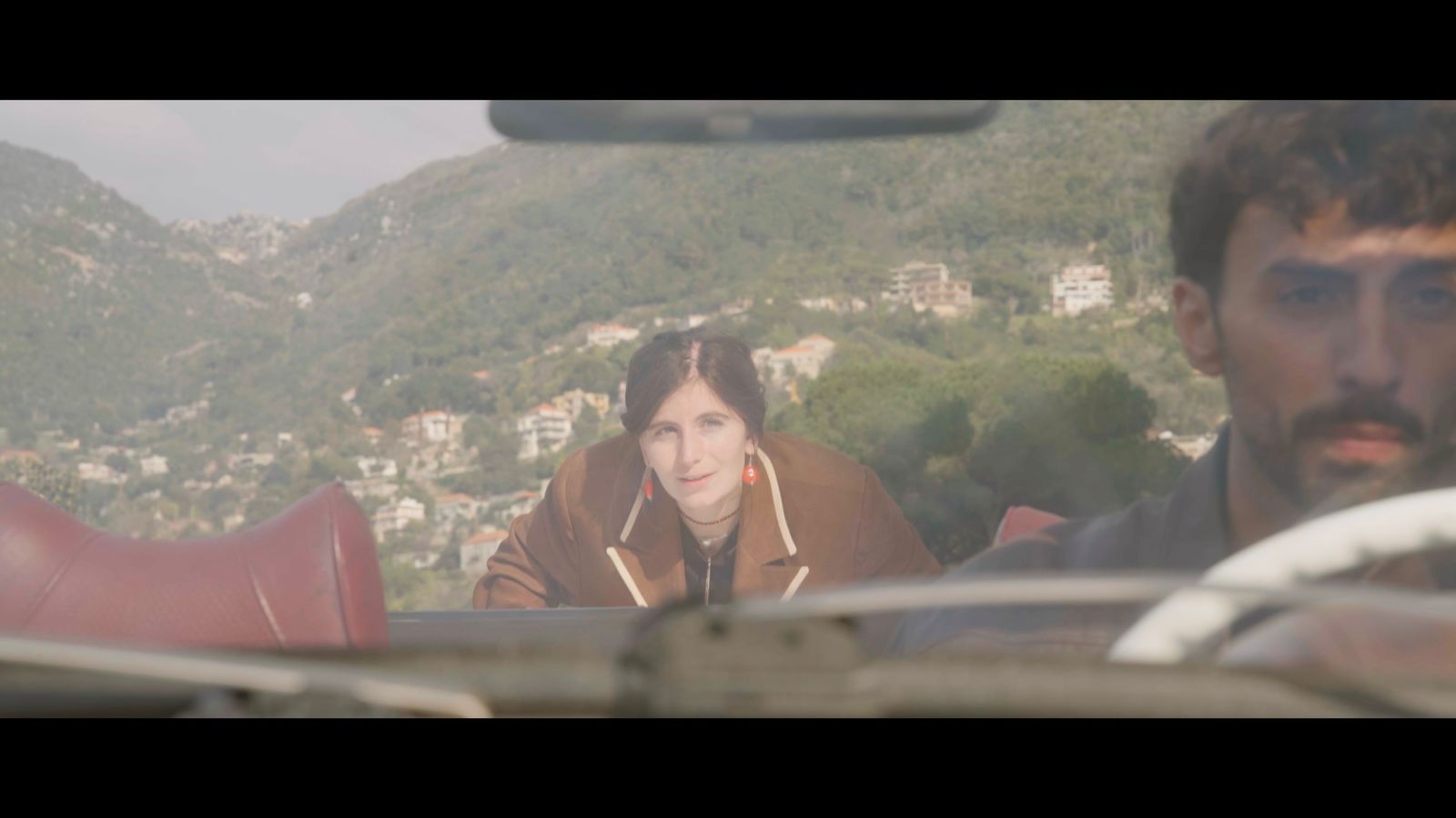 Film still viewed through the windshield of a convertible