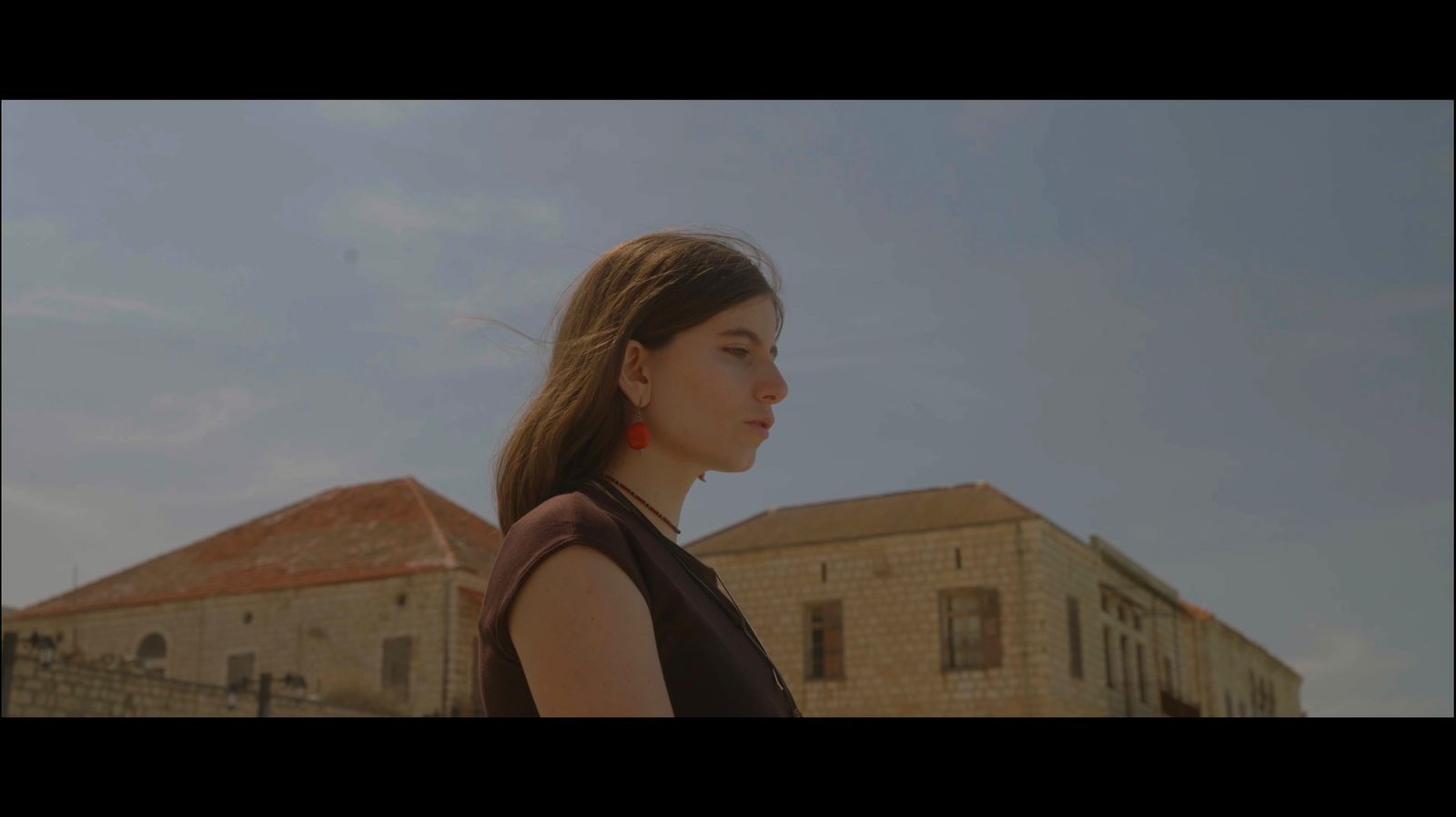 Film still of a woman in profile beneath a wide sky
